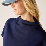 Woman wearing a navy blue top and denim cap on a plain background