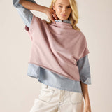 Woman wearing a pink scarf over a light blue shirt with a beige background