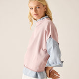 Woman wearing a pink and denim color-blocked sweater on a beige background