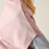 Person wearing a pink poncho over a gray outfit on a plain background