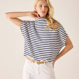 Woman wearing a black and white striped shirt with white pants on a beige background