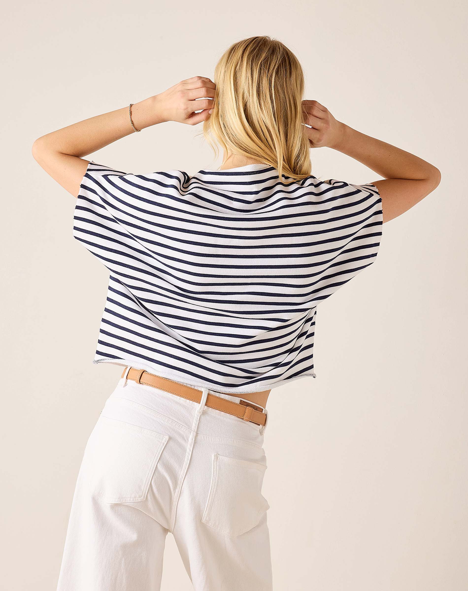 Person wearing a black and white striped shirt with a beige background