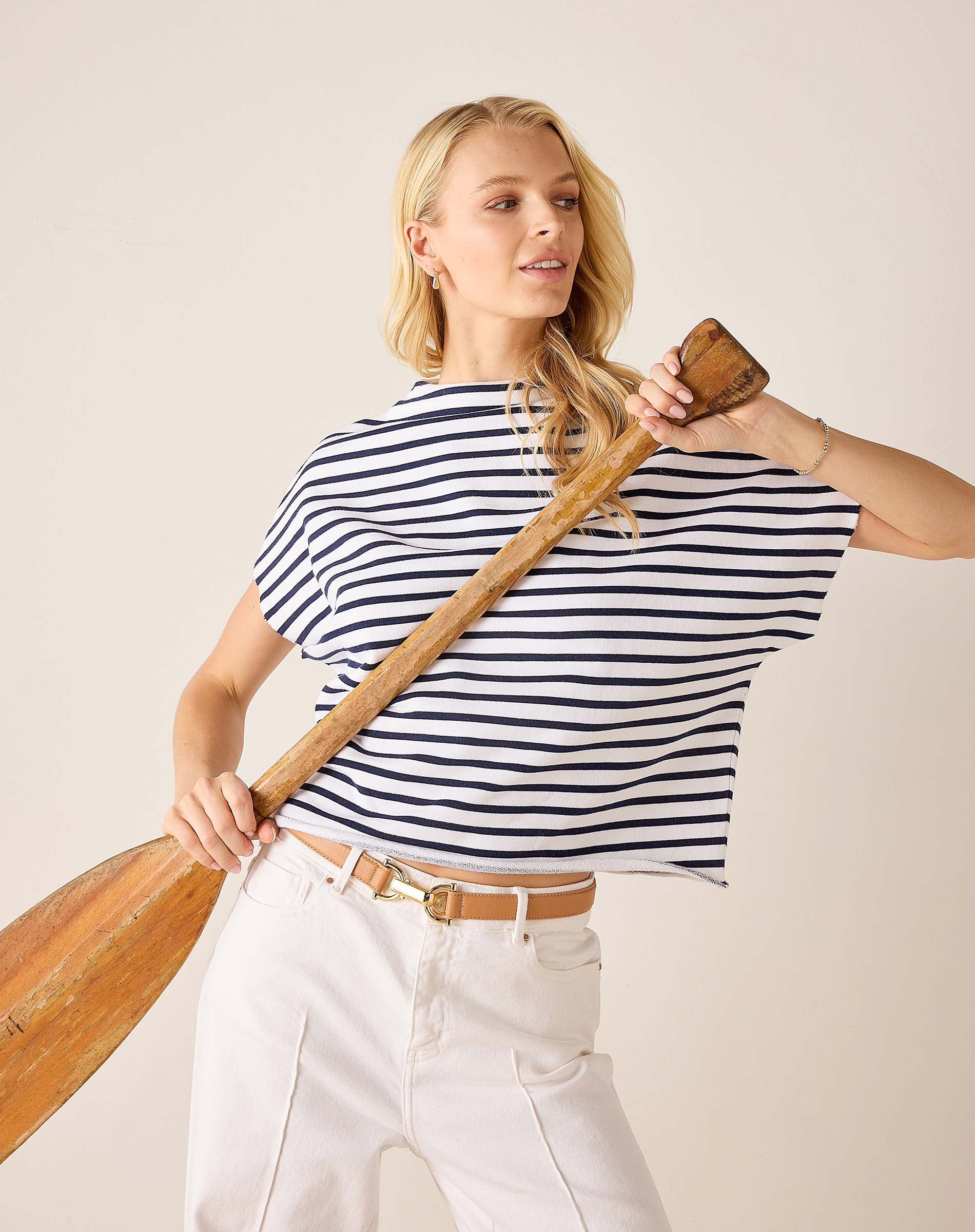 Woman holding a wooden oar against a plain background