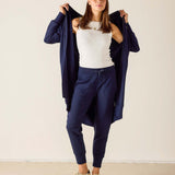 Woman wearing a navy outfit with a white top against a plain background