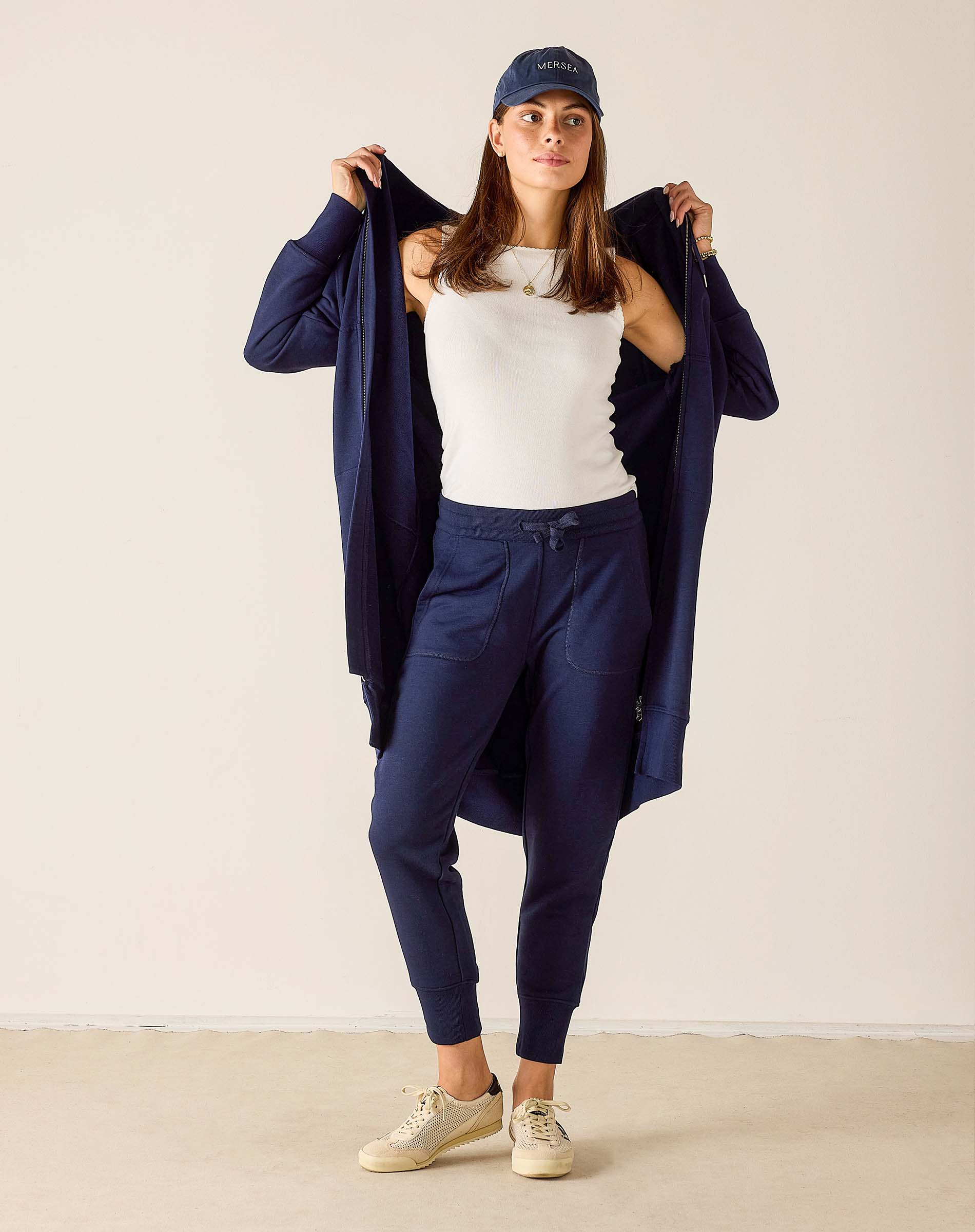 Woman wearing a navy outfit with a white top against a plain background
