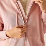 Person wearing a light pink jacket with a neutral background