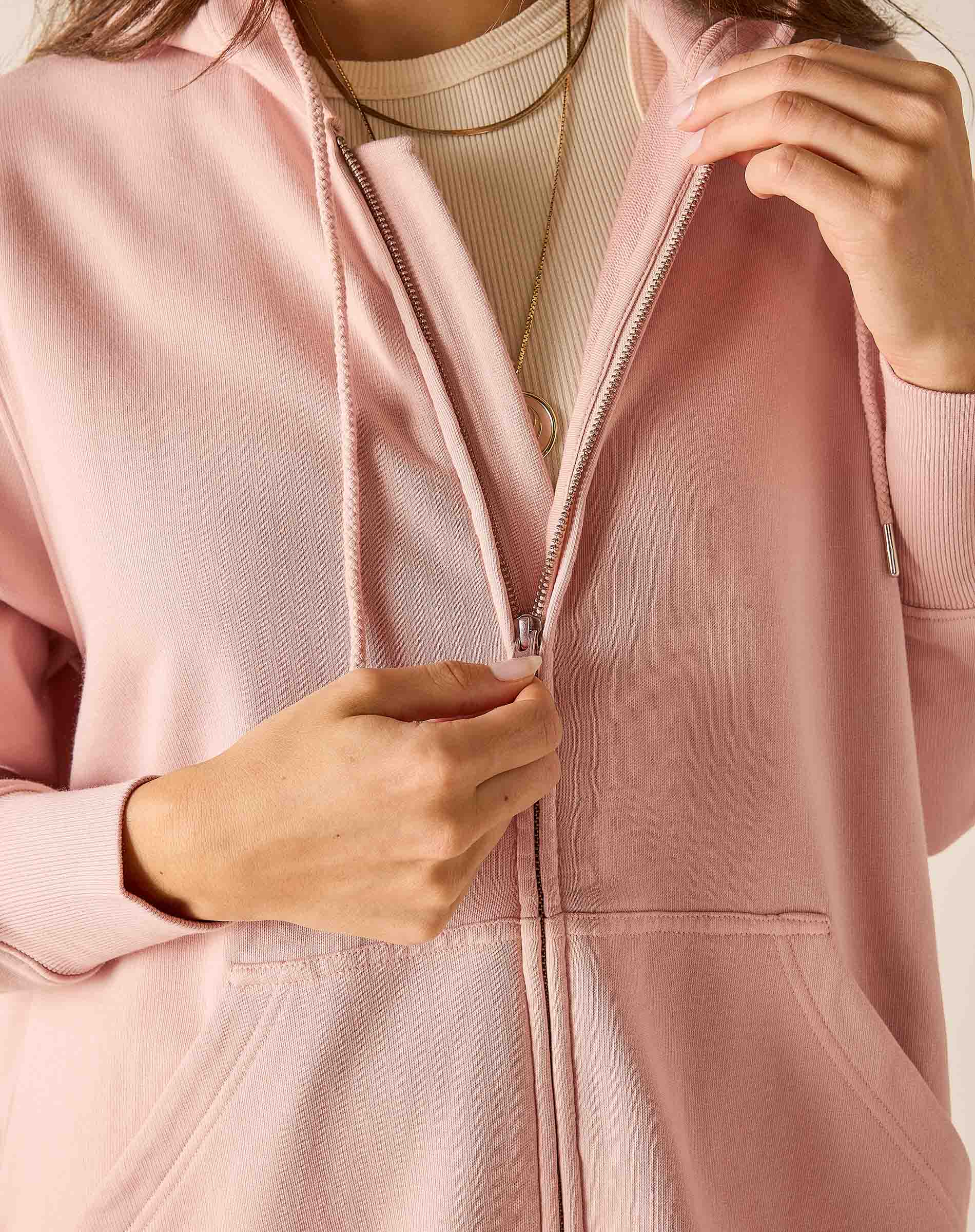 Person wearing a light pink jacket with a neutral background