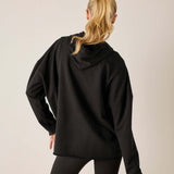 Back view of women's travel-friendly black hoodie with a drawstring hood and dropped shoulders.