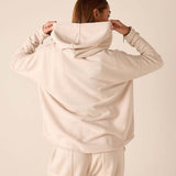 Back view of women's travel-friendly bone hoodie featuring a large hood and oversized fit.