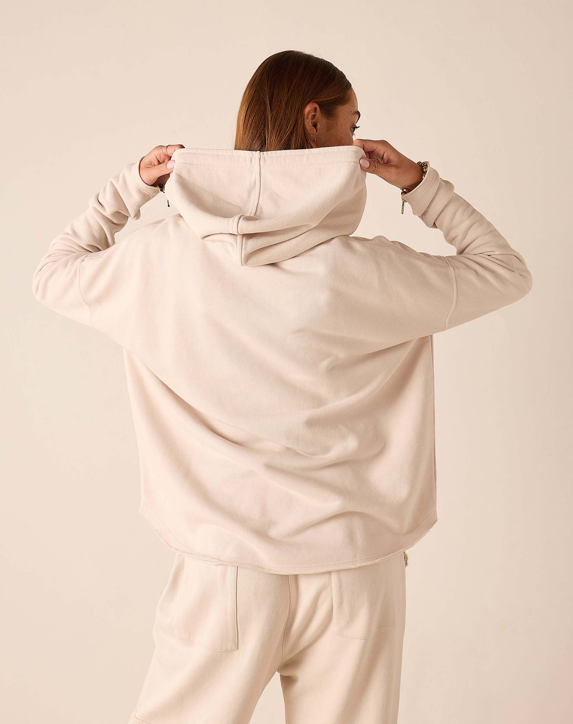 Back view of women's travel-friendly bone hoodie featuring a large hood and oversized fit.
