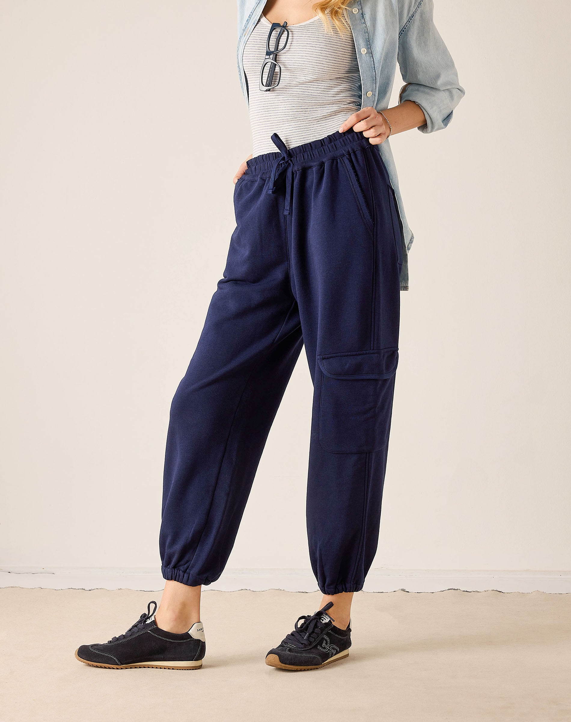 Person wearing navy cargo pants with a neutral background