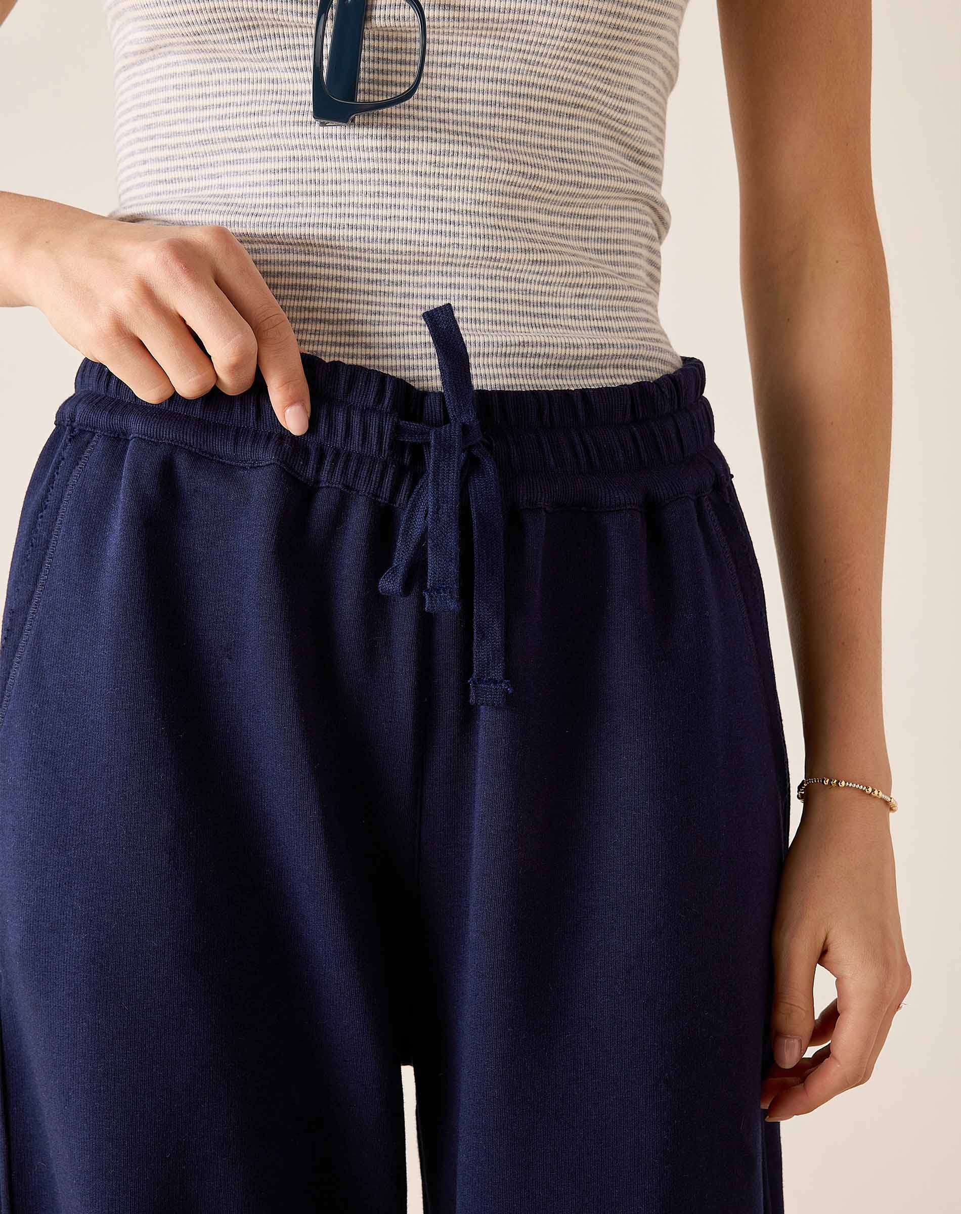 Navy blue pants with a drawstring waist worn by a person on a neutral background