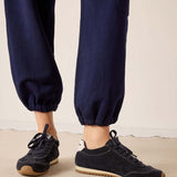 Navy jogger pants with black sneakers on a neutral background
