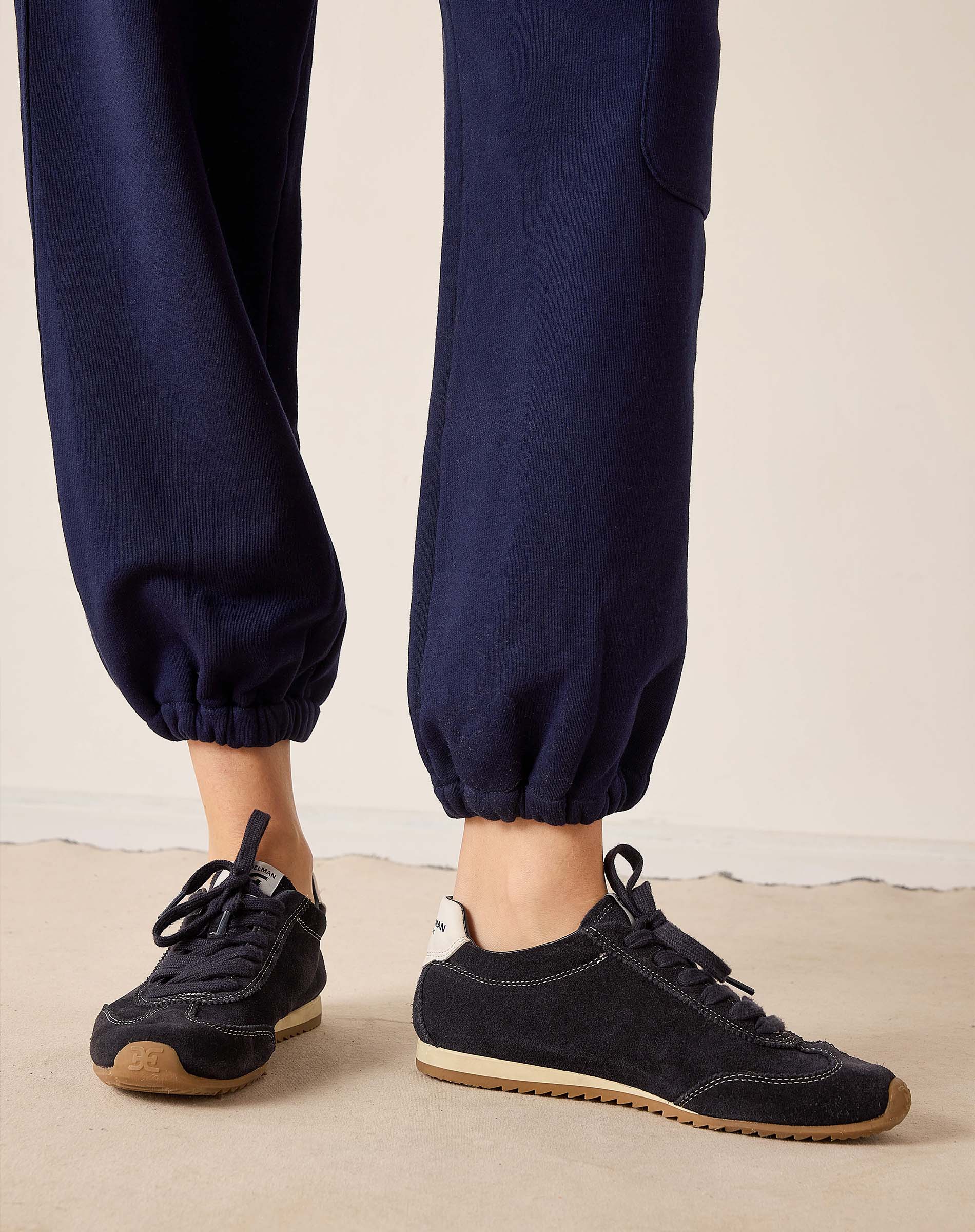 Navy jogger pants with black sneakers on a neutral background