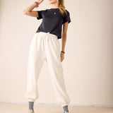 Person wearing a navy t-shirt, white pants, and a cap on a plain background