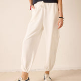 Person wearing white pants and Adidas sneakers on a plain background