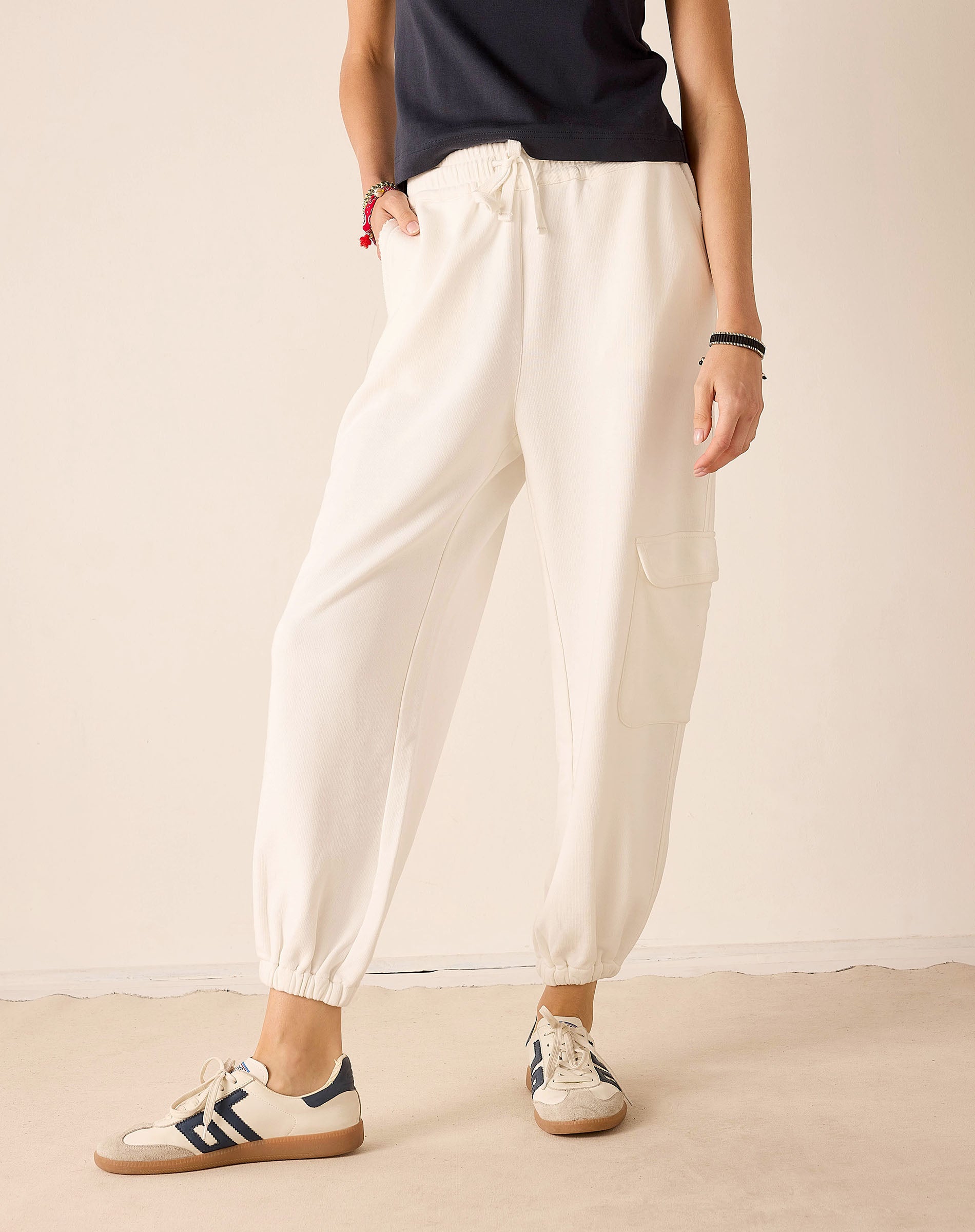 Person wearing white pants and Adidas sneakers on a plain background