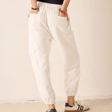 Person wearing white pants and navy shoes on a plain background