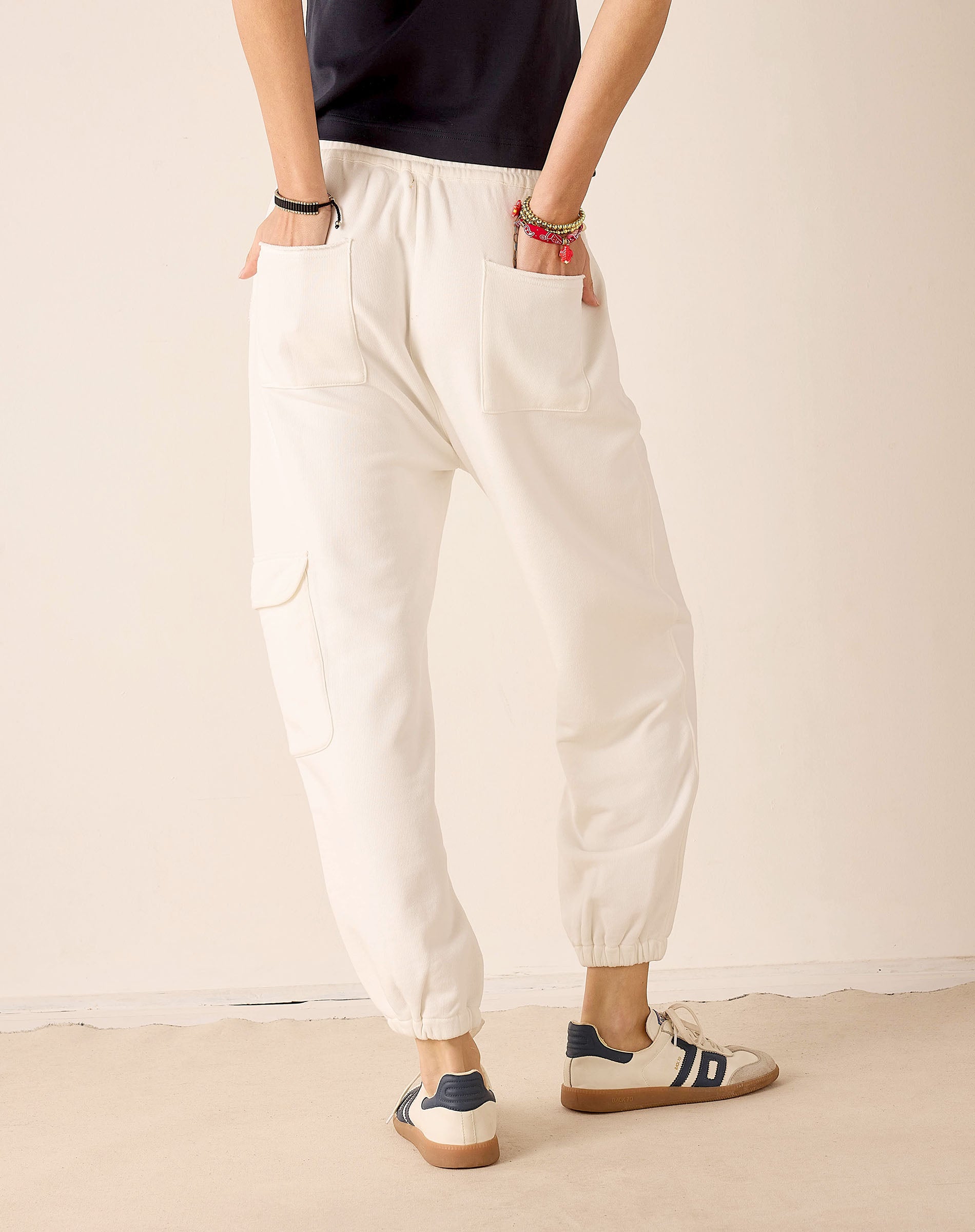 Person wearing white pants and navy shoes on a plain background