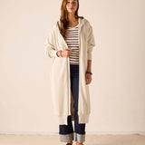 Bone hoodie featuring a longer length and hood, worn over a striped top and jeans.