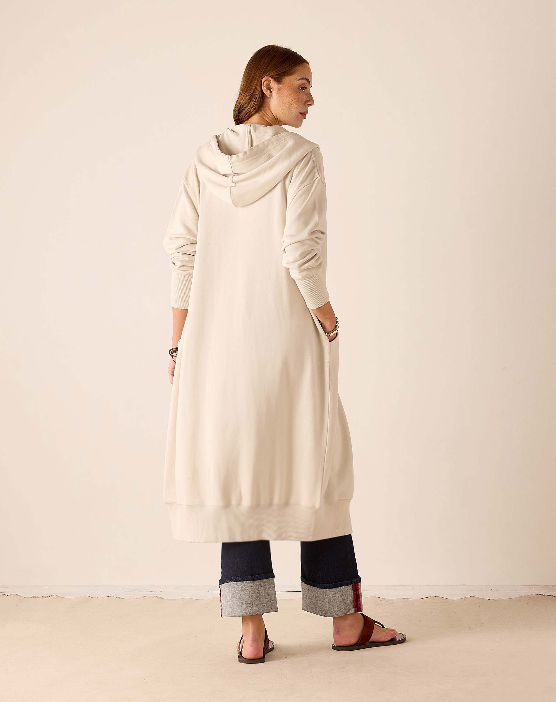 Back view of the bone-colored maxi hoodie with a large hood and ribbed cuffs.