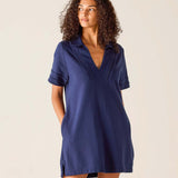 Woman wearing a navy blue dress against a beige background