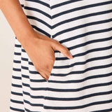 Close-up of a person wearing a white dress with navy blue stripes, holding their hand in a pocket.