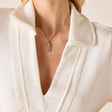 Close-up of a person wearing a white blouse with a necklace.