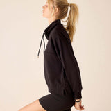 Side view of the black quarter-zip sweatshirt with a hood and matching shorts.