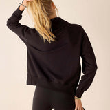 Back view of women's travel-friendly black quarter-zip sweatshirt with a relaxed fit and ribbed hem.