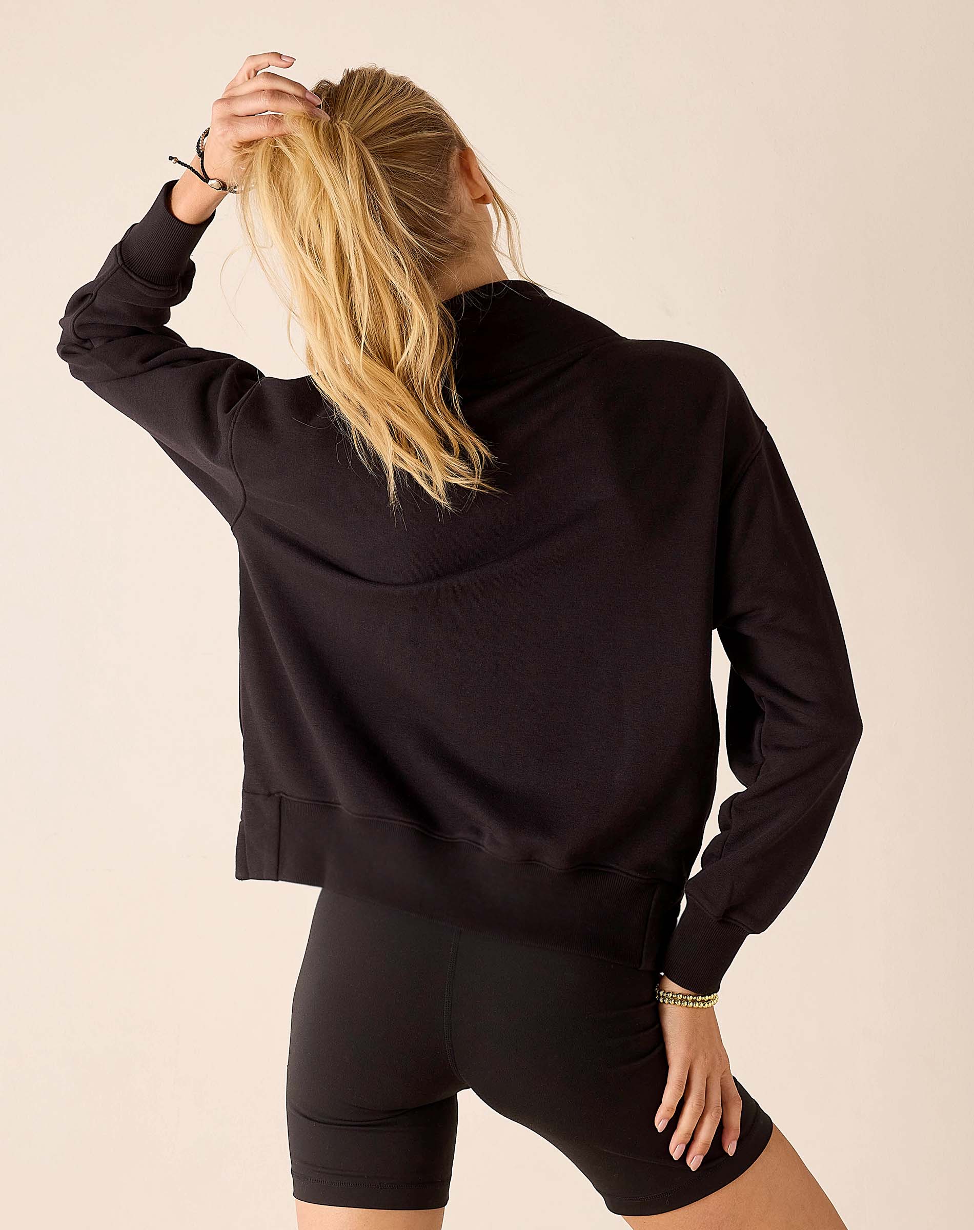 Back view of women's travel-friendly black quarter-zip sweatshirt with a relaxed fit and ribbed hem.