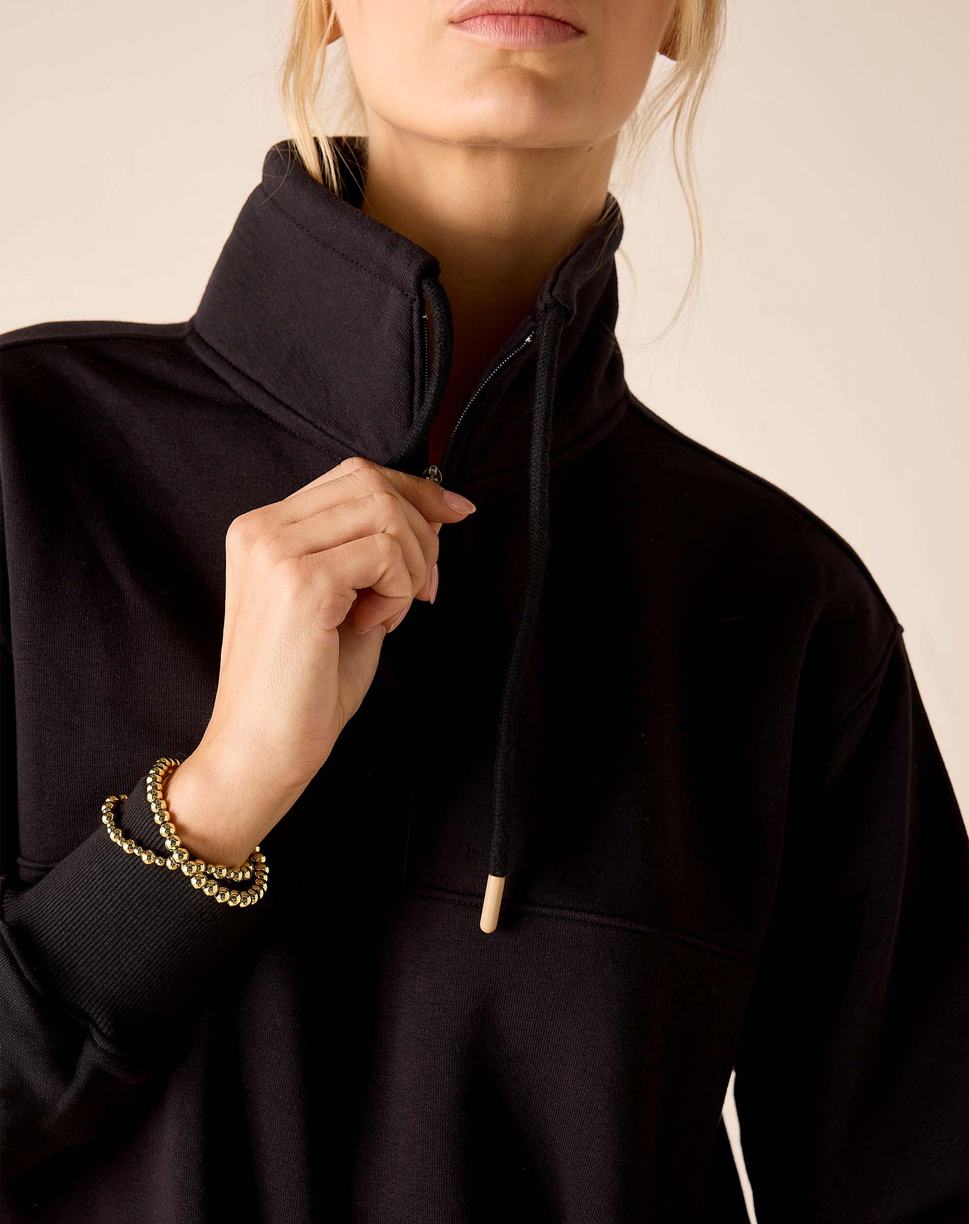 Black Frenchie quarter-zip sweatshirt with a high collar and gold-tipped drawstrings.
