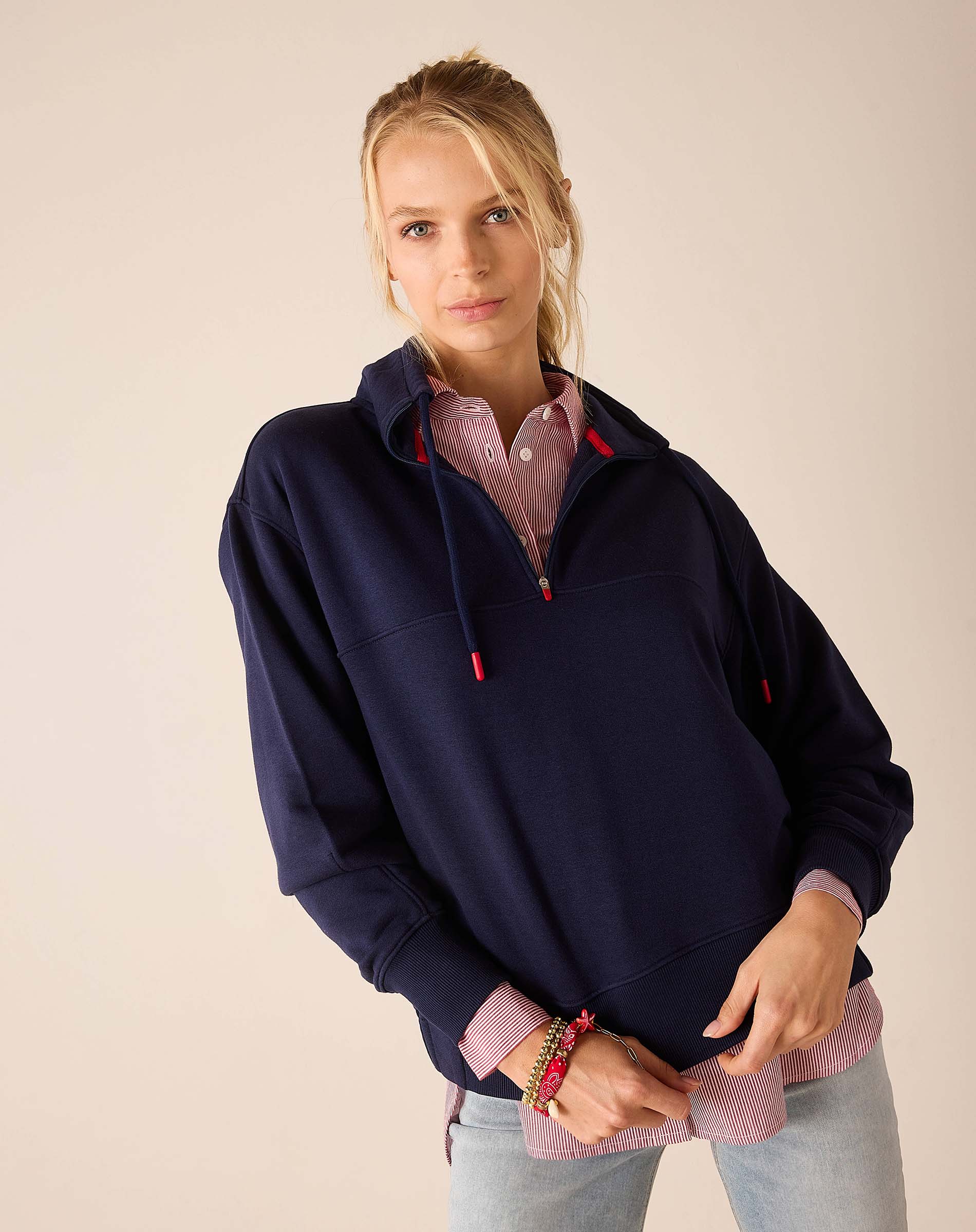 Cadet blue quarter-zip sweatshirt with a checkered button-down shirt layered underneath.
