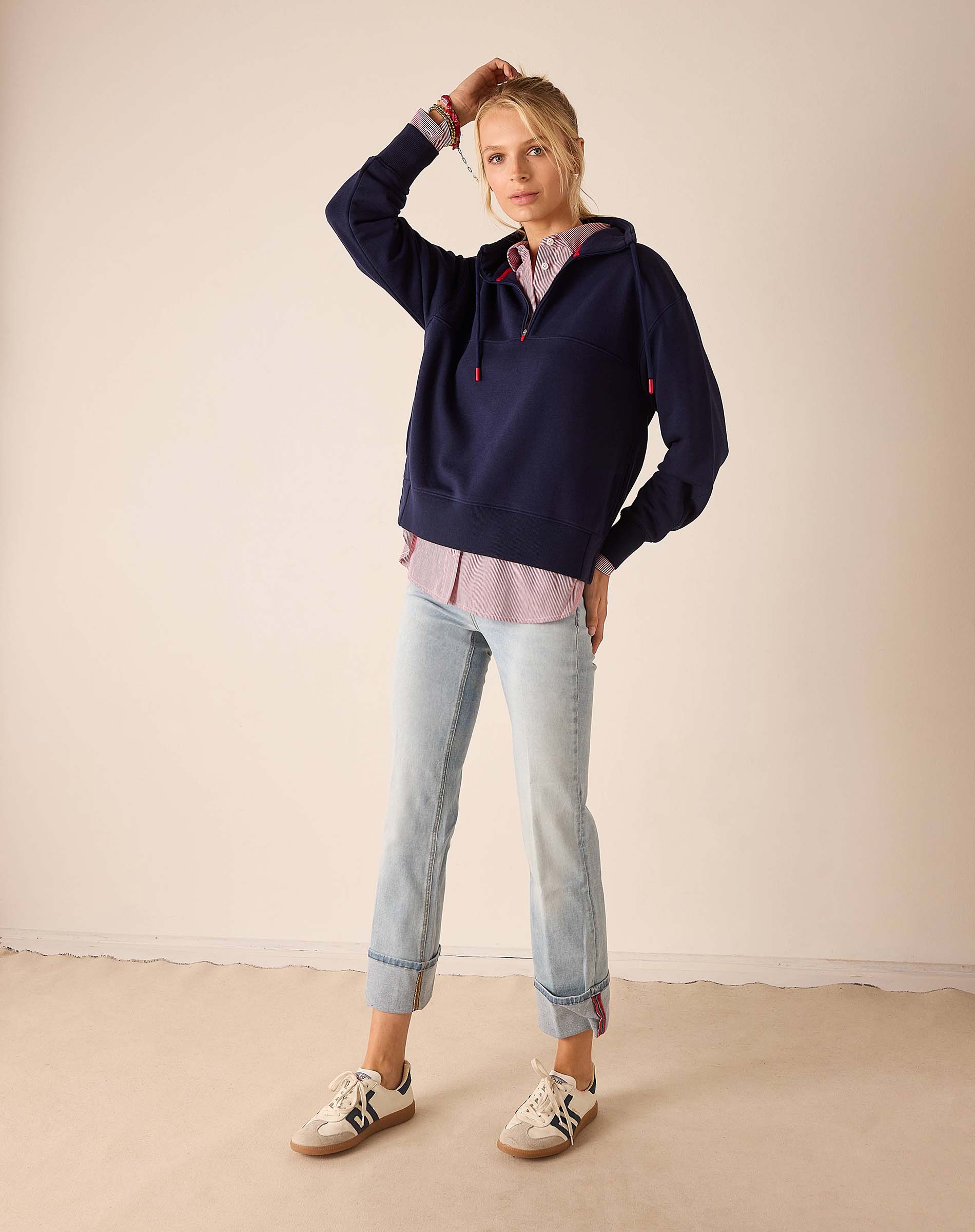 Cadet blue quarter-zip sweatshirt with a layered look and light wash jeans.