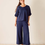 Woman wearing a navy blue outfit with wide-leg pants against a plain background
