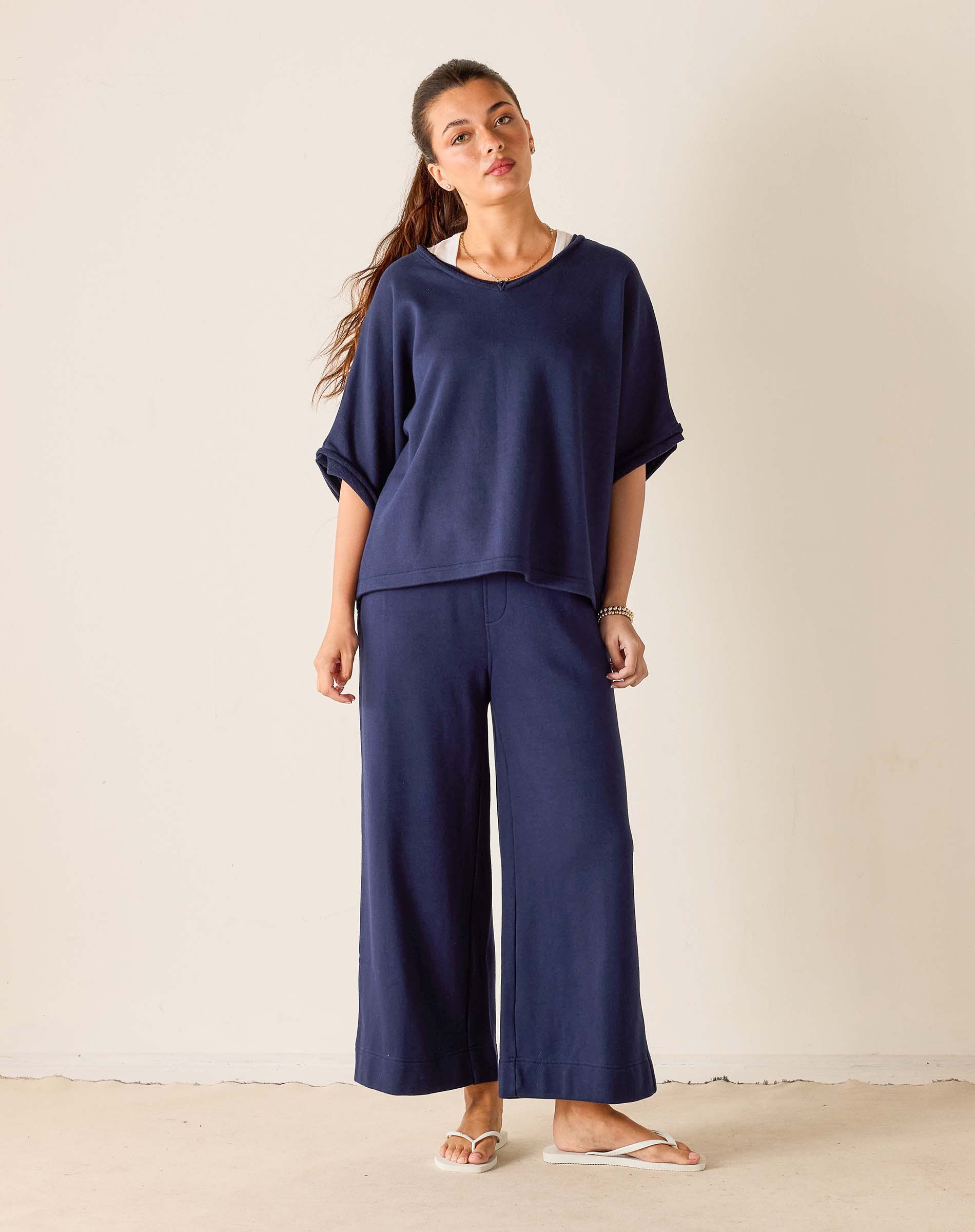 Woman wearing a navy blue outfit with wide-leg pants against a plain background