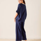 Woman wearing a navy blue outfit standing against a plain background