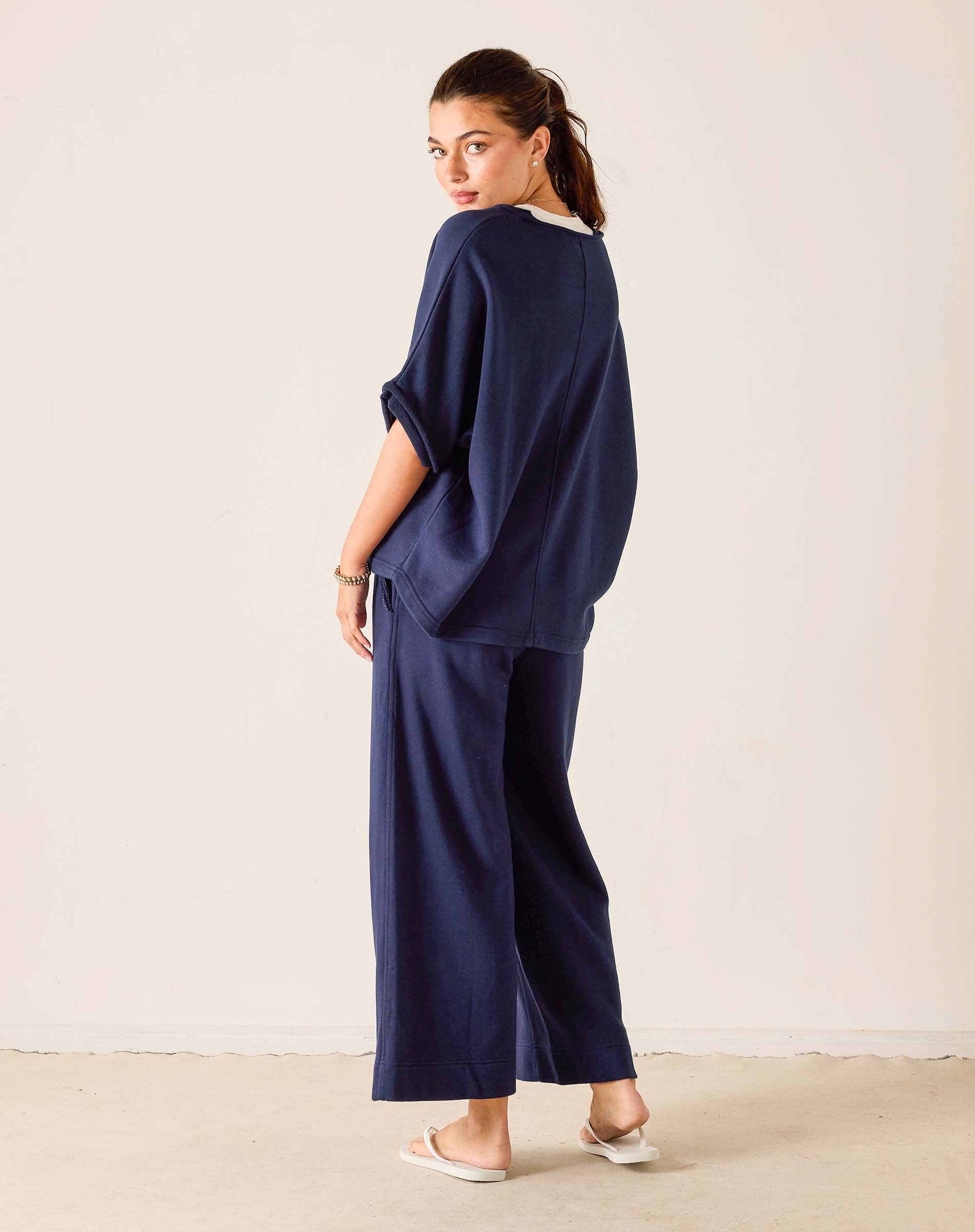 Woman wearing a navy blue outfit standing against a plain background