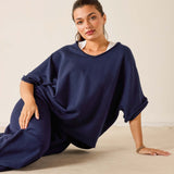 Woman wearing a navy blue dress sitting on a beige floor against a white wall