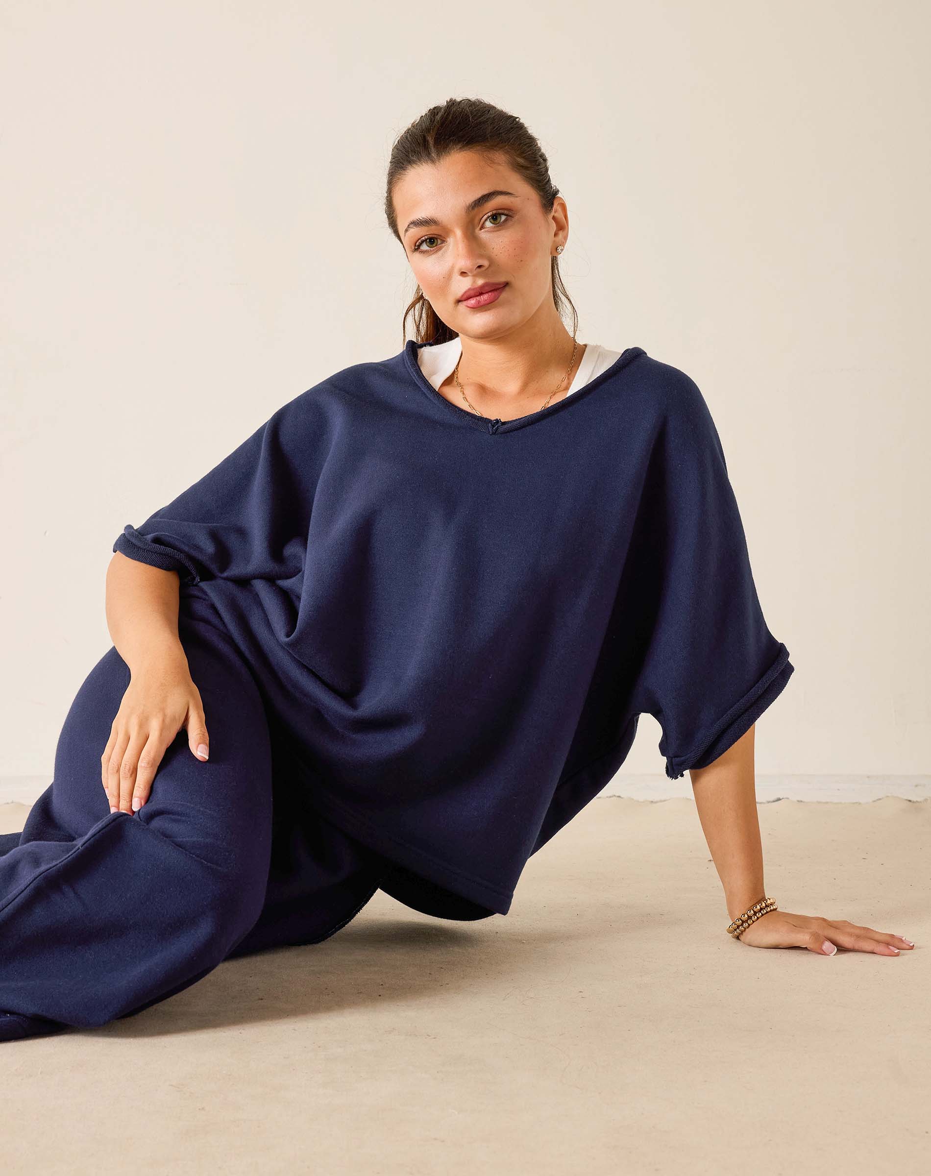 Woman wearing a navy blue dress sitting on a beige floor against a white wall