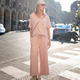 Person wearing a light pink outfit standing on a city street.