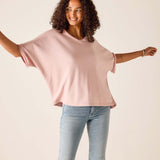 Woman wearing a pink oversized t-shirt and light blue jeans against a beige background
