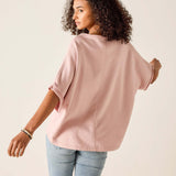 Woman wearing a light pink oversized shirt and light blue jeans on a beige background