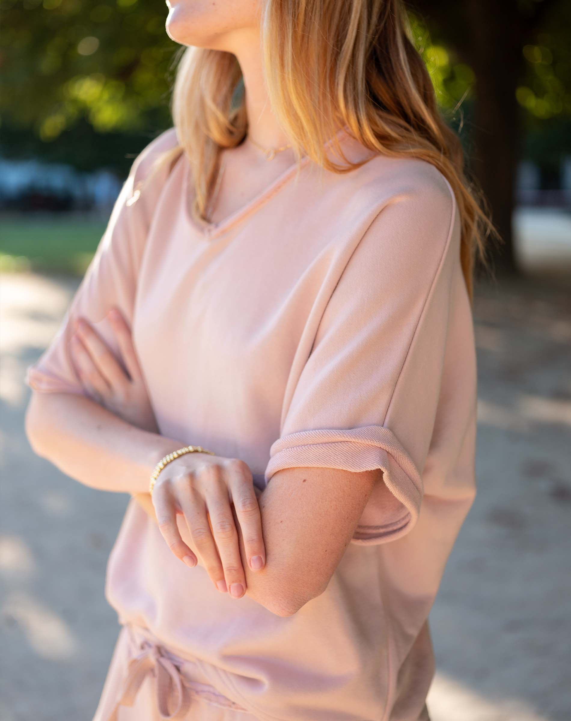 Woman wearing a light pink dress with a blurred outdoor background