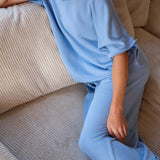 Person wearing a blue outfit sitting on a beige couch
