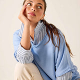 Woman wearing a light blue scarf over her shoulders with a neutral background