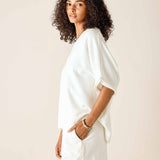 Woman wearing a white outfit against a plain background