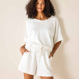 Woman wearing a white outfit against a plain background