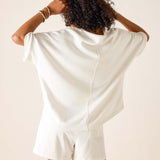 Person wearing a white satin romper against a beige background