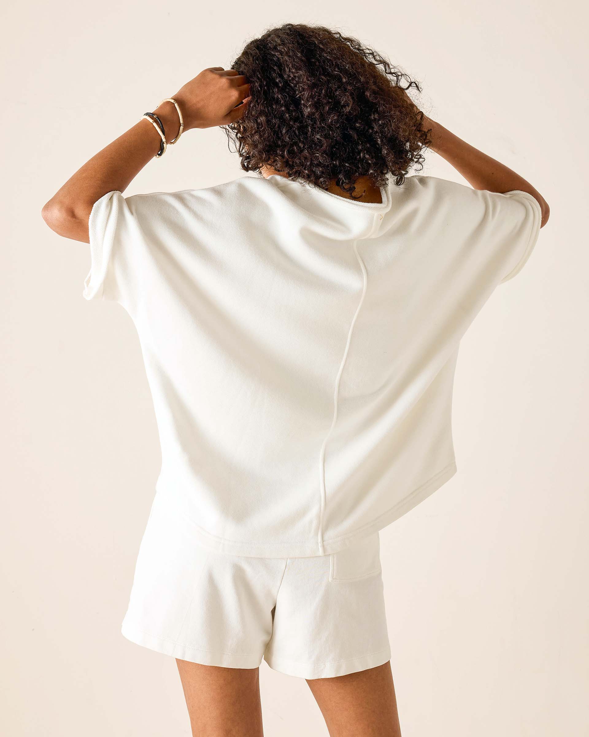 Person wearing a white satin romper against a beige background